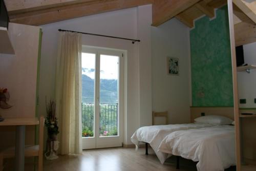 een slaapkamer met een bed en een groot raam bij Agritur Due Valli in Livo