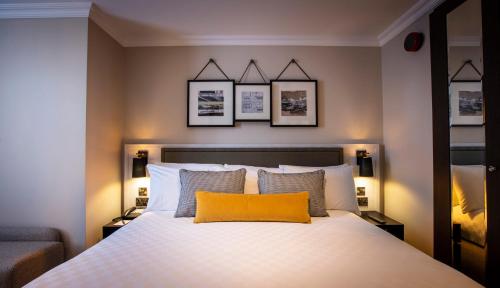 a bedroom with a bed with a yellow pillow on it at The Clermont London, Victoria in London