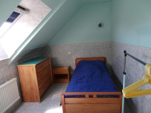 ein Schlafzimmer mit einem blauen Bett in einem Dachgeschoss in der Unterkunft Le Cottage " Village de La Ruée " Location de vacances in Plurien
