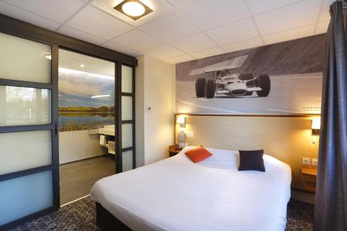 une chambre d'hôtel avec un lit et une photo d'une voiture sur le mur dans l'établissement Logis Relais Des Puys, à Orcines