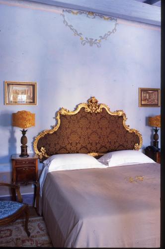 a bedroom with a large bed with a gold headboard at Locanda Pietrasantese B&B in Pietrasanta