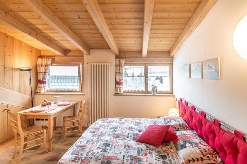 een slaapkamer met een rood bed en een tafel bij Holiday Apartments Val Moena in Cavalese
