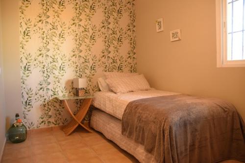 Un pequeño dormitorio con una cama y una mesa. en CASA CAPELLANIA-chalet con piscina junto a Madrid, en Méntrida
