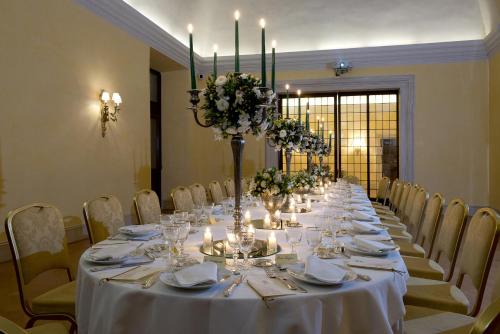 a long table with white tablecloths and flowers and candles at Palazzo Cardinal Cesi in Rome