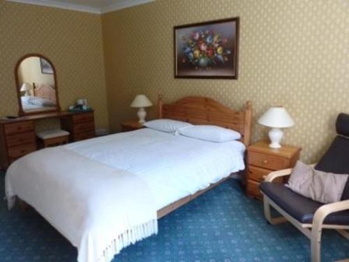 a bedroom with a large white bed and a chair at Tayburn House in Dunkeld