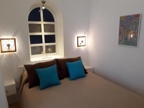 a room with a couch with blue pillows and a window at Dar es Salam-Baja in Asilah