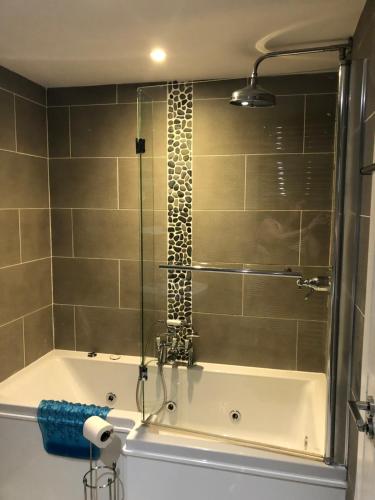 a bathroom with a bath tub with a shower at Buckfield Roost. 3 bedroom Newlyn Home in Newlyn