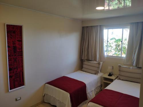 a hotel room with two beds and a window at Hotel Maea Hare Repa in Hanga Roa