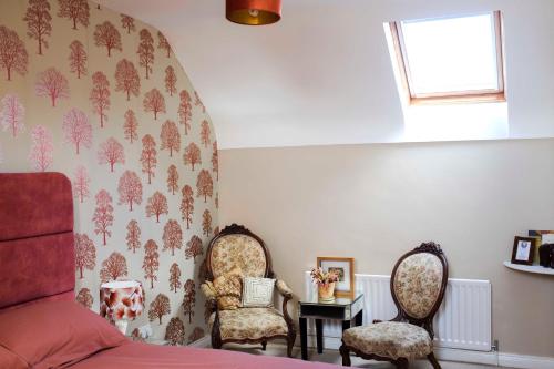 a bedroom with two chairs and a bed and a window at Old Schoolhouse B and B in Enniskillen
