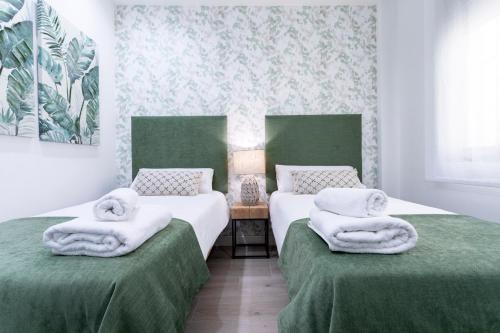 2 camas con toallas en un dormitorio en Livemalaga Balneario Beach, en Málaga
