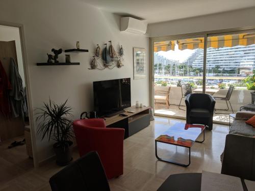 a living room with a flat screen tv and chairs at French Riviera Condo 4 Rent in Marina Baie des Anges in Villeneuve-Loubet