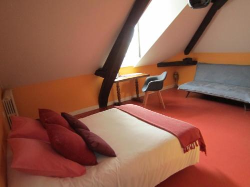 a bedroom with a bed with red pillows and a chair at Le Camélia in Ruillé-Froid-Fonds