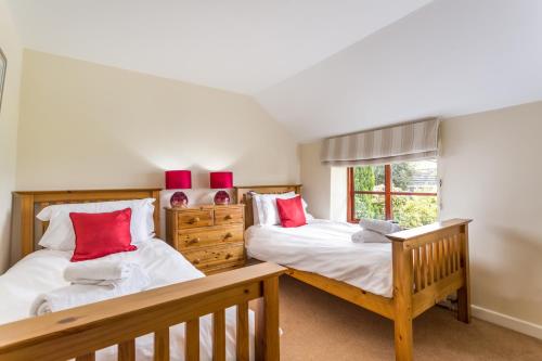 two beds in a room with red pillows at Red Doors Farm Cottages in Honiton
