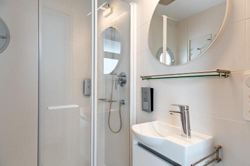uma casa de banho com um chuveiro, um lavatório e um espelho. em Apartamentos y estudios céntricos Conil Home Suite em Conil de la Frontera