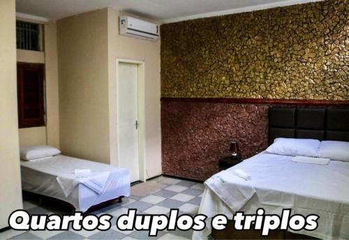 a bedroom with two beds and a wall at Hotel Nacional in Sobral