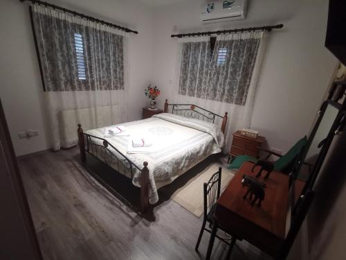 a bedroom with a bed and a chair and windows at Kalamospito Holiday House in Kalokhorio