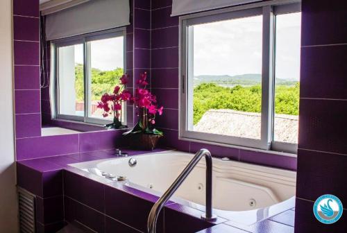 baño púrpura con bañera y ventana en Hotel Campestre El Cisne en Barranquilla