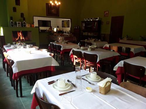 a restaurant with white tables and chairs and a fireplace at Pousada Moinho Azul in Teresópolis