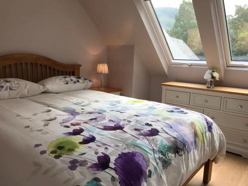 a bedroom with a bed with a floral comforter at River cottage in Fort William