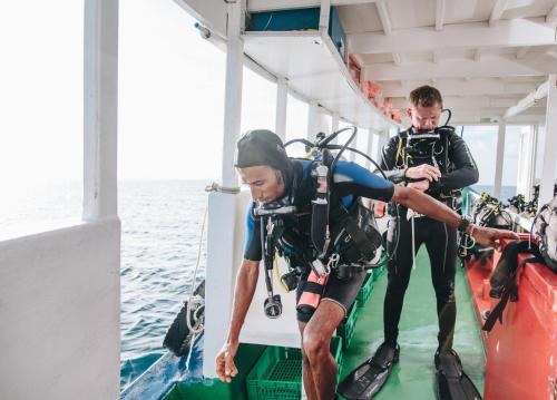 two men in scuba gear on a boat in the water at WAVE SOUND by 3S Maldives in Maradhoofeydhoo