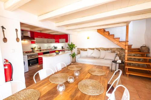 a kitchen and living room with a wooden table and chairs at Oliveira Surf House Ericeira in Santo Isidoro