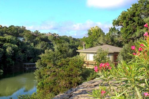 a house on a hill next to a river at Lakefront Treehouse on Lake Travis Pool & Hot Tub in Lakeway