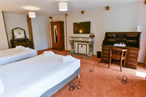 a room with two beds and a television and a fireplace at Hotel De Gramont in Pau