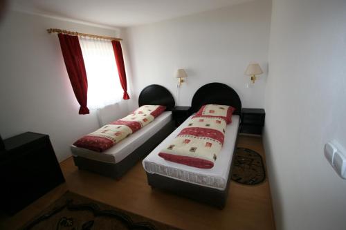 two beds in a small room with a window at Penzión Valentína in Poprad