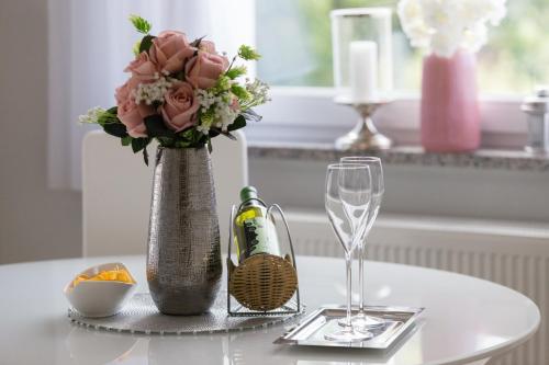a table with a vase with flowers and a wine glass at Apartment Snježana in Slunj
