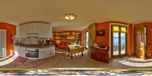 CasAle Fe-Wo - Appartamenti con vista Lago في كانيرو ريفييرا: مطبخ وغرفة معيشة بجدران برتقالية