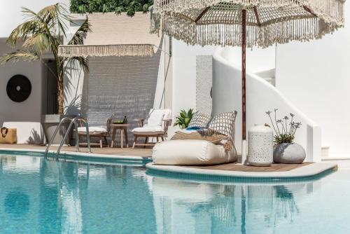 a swimming pool with an umbrella and chairs and a table at Virtu Suites in Agios Prokopios
