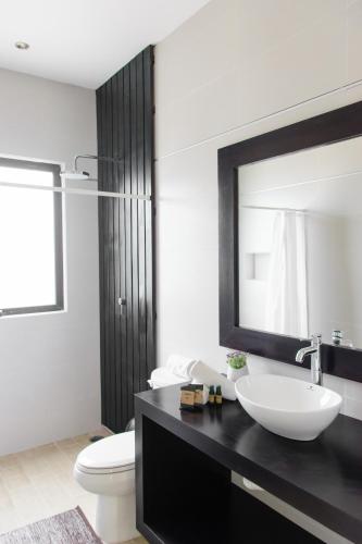 a bathroom with a sink and a toilet and a mirror at Che Suites Tulum in Tulum