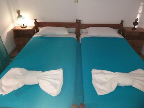 a blue bed with two beds with bow ties on it at Nikolettas Apartments in Faros