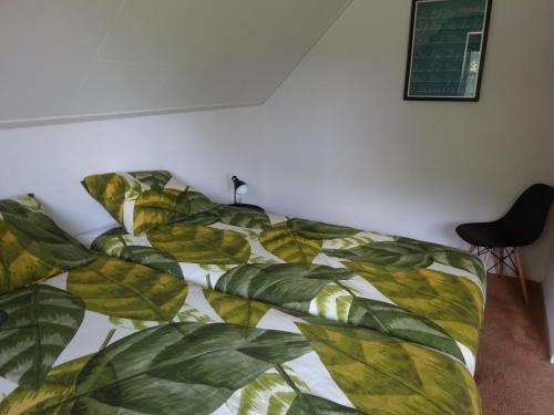 a bed with a green and yellow blanket on it at Holiday Home Zeewolde in Zeewolde