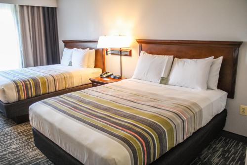a hotel room with two beds and a lamp at Country Inn & Suites by Radisson, Washington Dulles International Airport, VA in Sterling