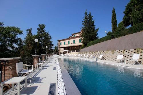 a swimming pool with white chairs and a building at Marchese Del Grillo in Fabriano