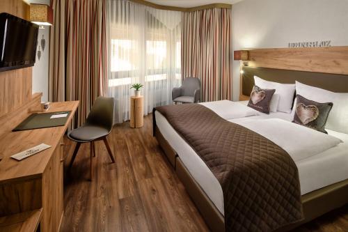 ein Hotelzimmer mit einem großen Bett und einem Schreibtisch in der Unterkunft Neo Hotel Linde Esslingen in Esslingen