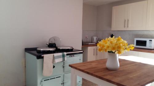 una cocina con un jarrón de flores amarillas sobre una mesa en Owl Cottage, en Hexham