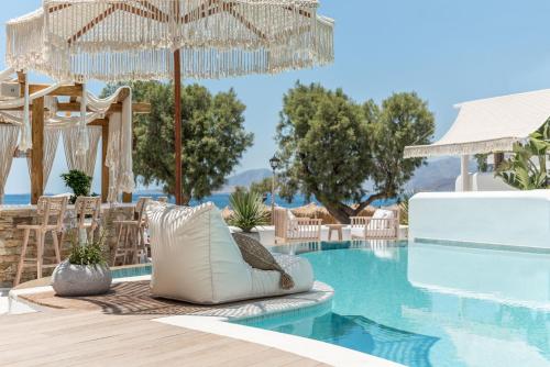 a pool at a resort with chairs and an umbrella at Virtu Suites in Agios Prokopios
