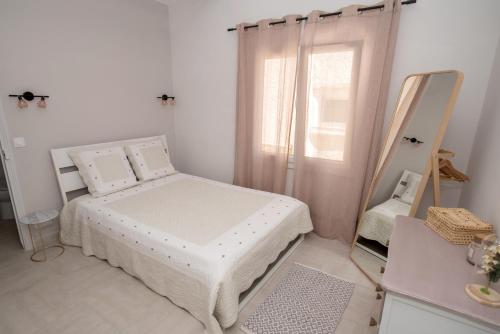 biała sypialnia z łóżkiem i lustrem w obiekcie Charmante petite maison a l'éntrée de Saint Tropez w Saint-Tropez