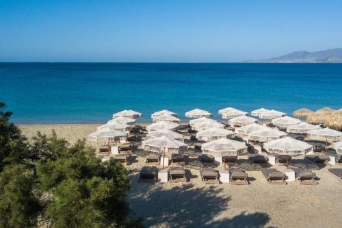 a group of white umbrellas and chairs on a beach at Virtu Suites in Agios Prokopios