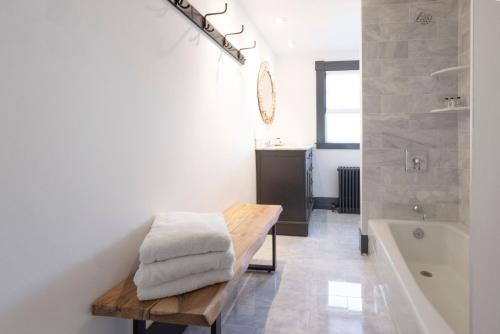 a bathroom with a wooden bench next to a bath tub at Addison Choate in Rockport