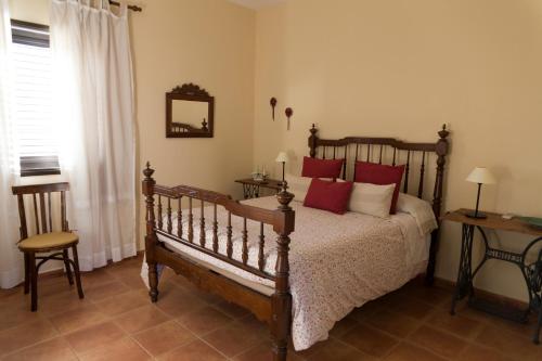 a bedroom with a wooden bed with red pillows at Los Olivos in Playa de Santiago