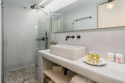 a white bathroom with a sink and a shower at Beach Suite Syrma in Pachaina
