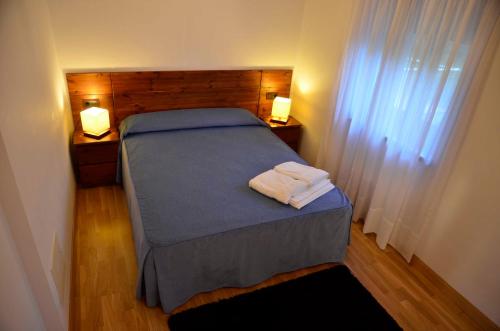 a bed in a room with two night stands and two lamps at Apartamentos Spa Cantabria Infinita in Cillorigo de Liebana