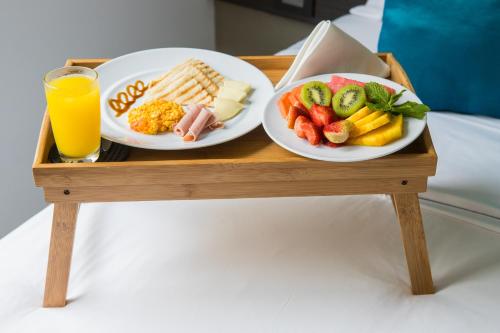 a tray with two plates of food and a glass of orange juice at Varanasi Hotel Boutique Aeropuerto in Cartagena de Indias