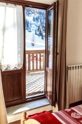 a bedroom with a door open to a porch with snow at Hotel Al Foiron in Claviere