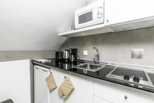 eine Küche mit einer Spüle und einer Mikrowelle in der Unterkunft Brand new and perfect location: historic center in Lissabon