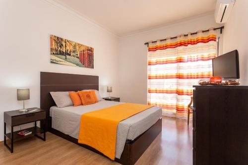 a bedroom with a bed with an orange blanket and a window at Graca House in Lisbon
