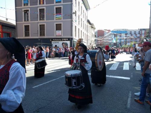 a group of people walking down a street with drums at La Quintana de Doña Leonor in Arriondas